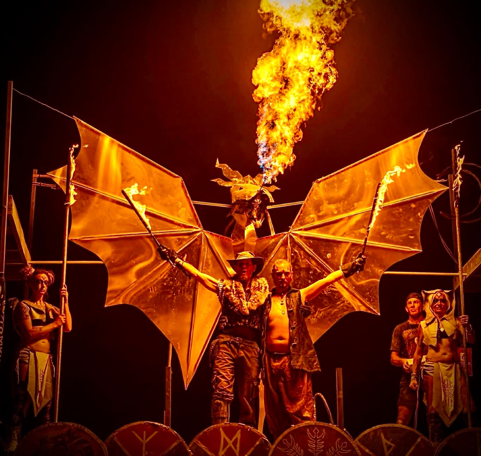 A dragon puppet breathes a column of fire above the shield wall